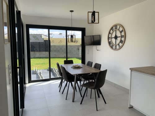 Salle à manger moderne à La Maison Blanche B&B à Bouguenais avec table, chaises noires et vue sur le jardin