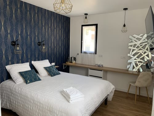 Chambre moderne à La Maison Blanche B&B à Bouguenais avec papier peint à motifs, literie blanche et décoration géométrique