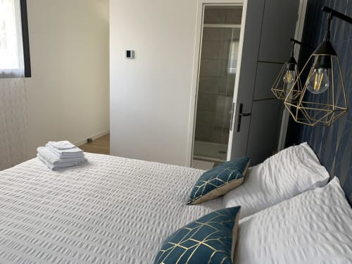 Camera moderna di La Maison Blanche B&B a Bouguenais con letto, cuscini blu e lampada a sospensione geometrica