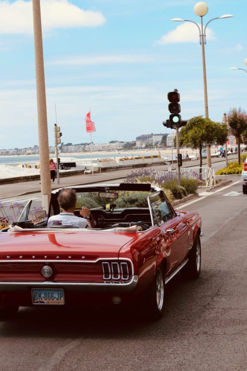 Cabriolet rosso d'epoca che percorre il lungomare presso La Maison Blanche, Bouguenais