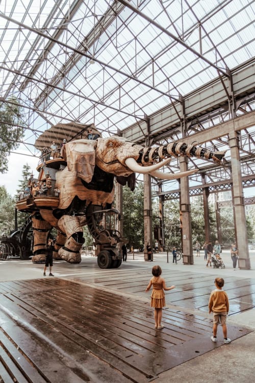 Scultura di elefante meccanico gigante a La Maison Blanche, Bouguenais - bambini che esplorano sotto la volta in vetro