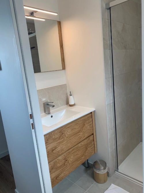 Bagno moderno presso La Maison Blanche BnB con mobile in legno, lavabo bianco, specchio illuminato e doccia walk-in