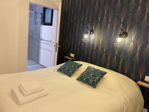 Camera moderna presso La Maison Blanche BnB a Bouguenais con letto bianco, cuscini turchesi, parete con motivi decorativi e lampade a sospensione