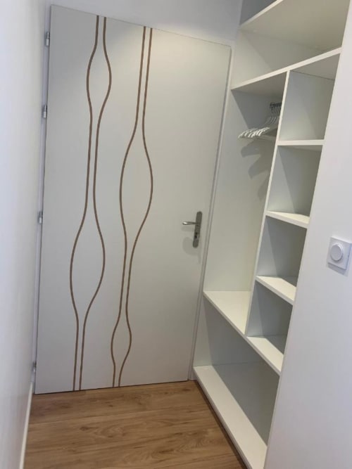 Ripostiglio moderno con scaffali bianchi e porta a motivi ondulati presso La Maison Blanche B&B a Bouguenais