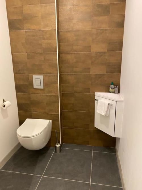Bagno moderno a La Maison Blanche B&B Bouguenais con piastrelle marrone, wc sospeso, vanità bianca e pavimento scuro