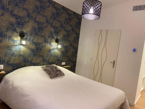Camera da letto moderna a La Maison Blanche B&B a Bouguenais con carta da parati azzurra a motivi, letto bianco e illuminazione contemporanea.