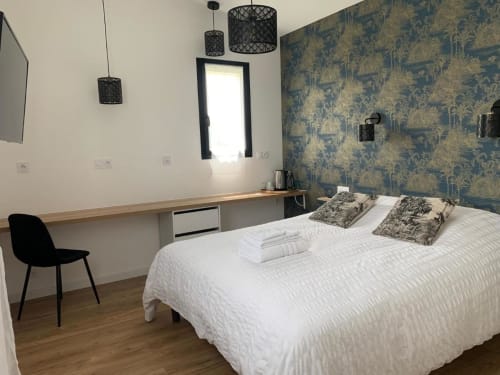 Camera moderna presso La Maison Blanche B&B a Bouguenais con letto bianco, carta da parati decorata, lampade a sospensione e zona di lavoro