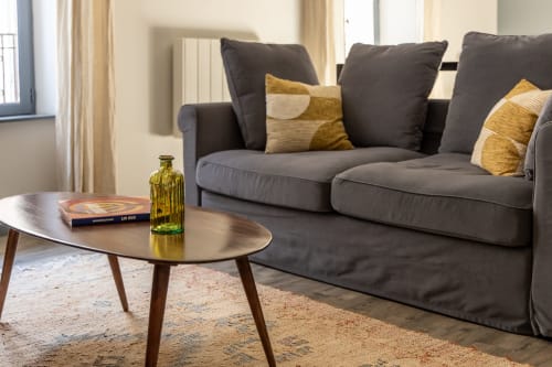 Modern living room at Le Prieuré Notre-Dame with gray sofa, golden accents, coffee table, and elegant decor in Montfrin