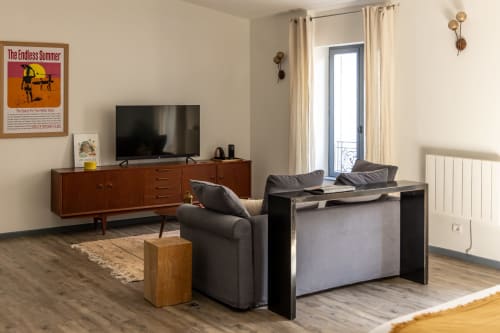 Spacious living room at Le Prieuré Notre-Dame with mid-century furniture, TV, and French doors overlooking landmark views