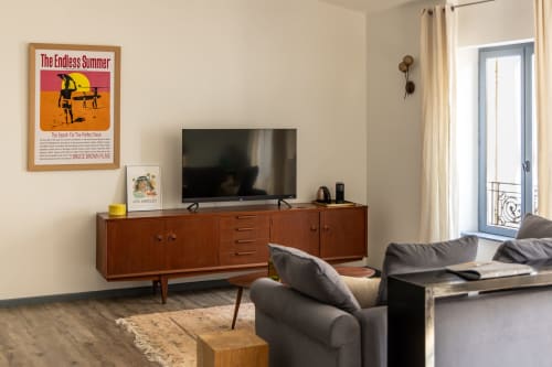 Modern living room at Le Prieuré Notre-Dame in Montfrin with mid-century wooden TV console and gray seating