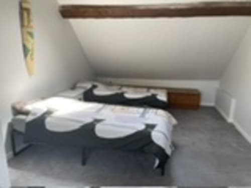 Cozy bedroom at Les Gites De Flaubert with dark bed, white pillows, and wooden beams in Le Heron