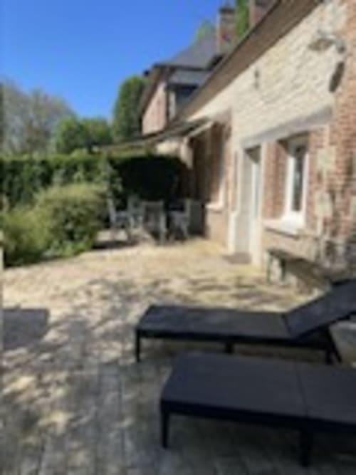 Rustic stone courtyard at Les Gites De Flaubert with loungers, garden views, and sunny patio area in le heron