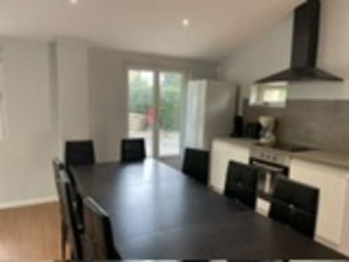 Modern dining area with black table and chairs, kitchen with hood vent at Les Gites De Flaubert in Le Heron, France