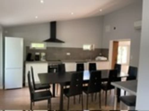 Modern open-plan kitchen and dining area at Les Gites De Flaubert with black chairs, dark cabinetry, and stainless steel