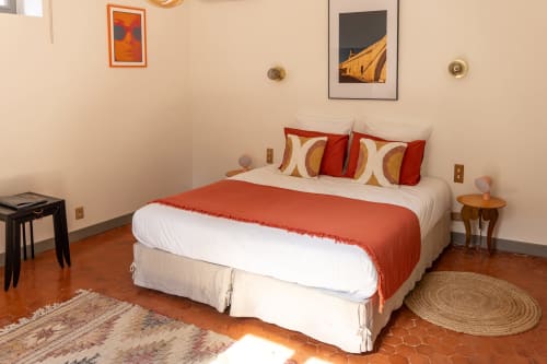 Madeleine Room at Le Prieuré Notre-Dame in Montfrin features a bed with red bedding, orange accents, and cream pillows.