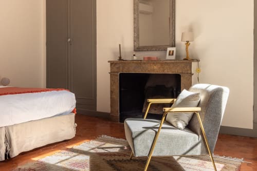 Madeleine Room at Le Prieuré Notre-Dame in Montfrin, France, featuring a bed, fireplace, and gray armchair
