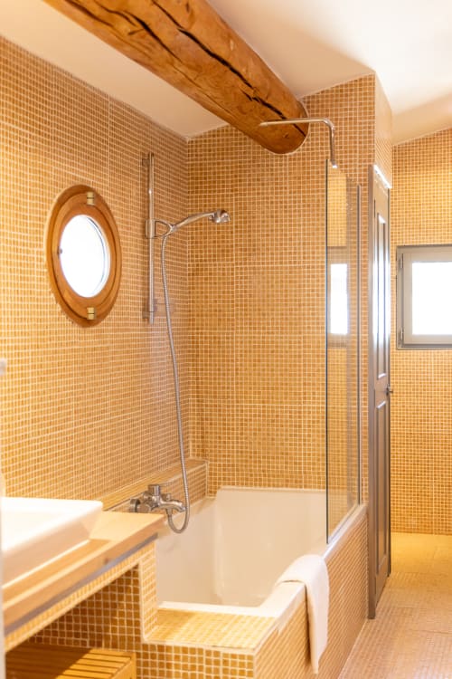 Luxury bathroom in Madeleine Room at Le Prieuré Notre-Dame, Montfrin with golden tile, soaking tub, and walk-in shower