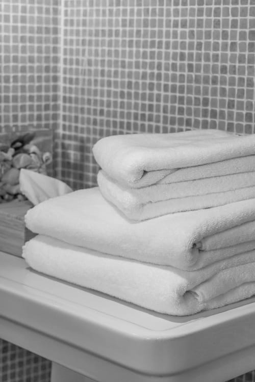 Stacked white towels on bathroom shelf at Le Prieuré Notre-Dame B&B in Montfrin