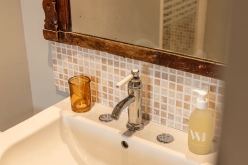 Lavabo moderne dans la Chambre Alphonse du Gîte Le Prieuré Notre-Dame avec robinetterie chromée, articles de toilette et dosseret carrelé