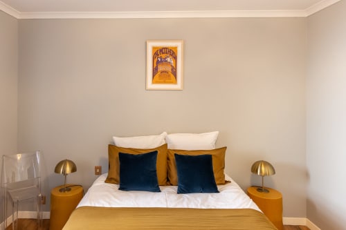 Chambre Alphonse au Prieuré Notre-Dame à Montfrin avec lit, coussins bleus et or, lampes en laiton et tableaux encadrés