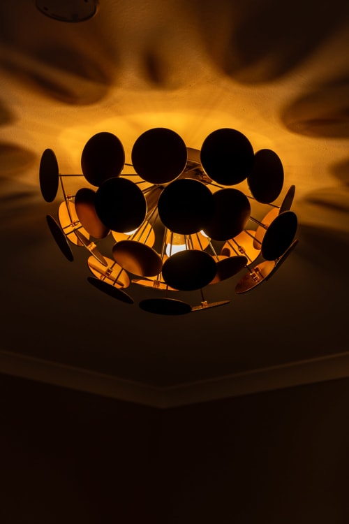 Luminaire de plafond moderne aux éléments sphériques diffusant une douce lumière dorée dans la chambre d'hôtes du Prieuré Notre-Dame