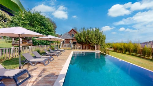 Luxe zwembad van Domaine De Campagnac met ligbedden, parasols, houten terras en uitzicht op het platteland in Carsac-Aillac, Frankrijk