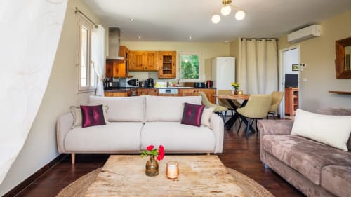 Helder woonkamer aan Domaine De Campagnac met beige bank, houten tafel en open keuken in Carsac-Aillac, Frankrijk