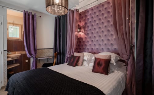 Luxe slaapkamer in Domaine De Campagnac met paarse gestoffeerde hoofdbord, hemelbed met vier posten en elegante gordijnen