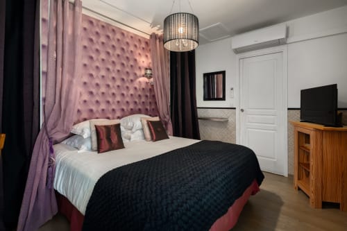 Elegante slaapkamer in Domaine De Campagnac met paarse gestoffeerde hoofdeinde, luifelgordijnen en moderne voorzieningen