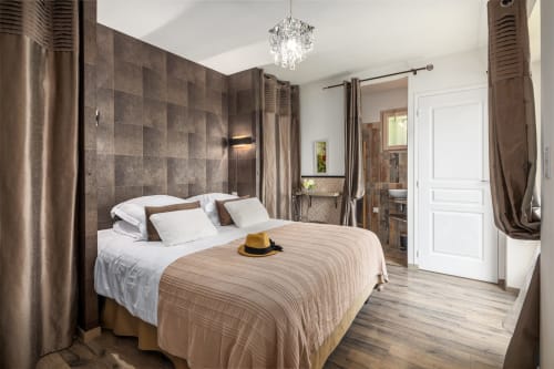 Ruime slaapkamer met betegelde accentmuur, wit beddengoed en ensuite badkamer in de cottage Domaine De Campagnac