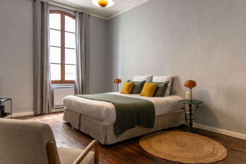 Modern bedroom at Le Prieuré Notre-Dame in Montfrin with bed, yellow accents, wooden floor, and landmark view window