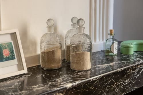 Elegant decorative perfume bottles with ornate glass stoppers on black marble dresser in François Room at Le Prieuré