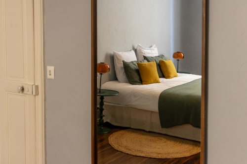 Cozy bedroom at Le Prieuré Notre-Dame with bed featuring yellow and green pillows, wooden nightstands, and natural light in