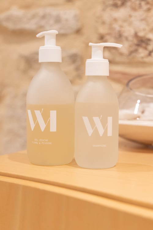 Two pump bottles of WI toiletries on wooden shelf in François Room at Le Prieuré Notre-Dame, Montfrin