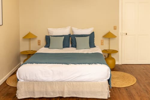 Elegantly styled bedroom at Le Prieuré Notre-Dame with blue and cream bedding, mustard lamps, and wooden floors in Montfrin