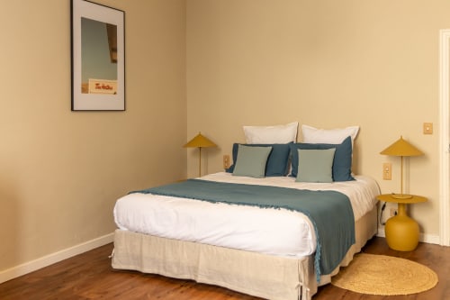 Cozy bedroom in Le Prieuré Notre-Dame with blue accents, gold lamps, and wooden floors in Montfrin