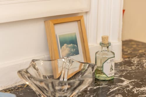 Elegant room detail at Le Prieuré Notre-Dame showing framed cloud artwork, glass decanter, and marble surface with natural