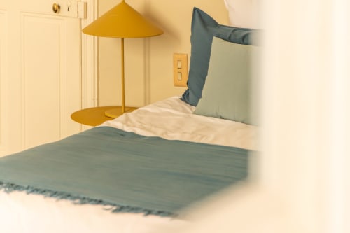 Modern bedroom at Le Prieuré Notre-Dame with blue bedding, gold pendant lamp, and cream walls in Montfrin