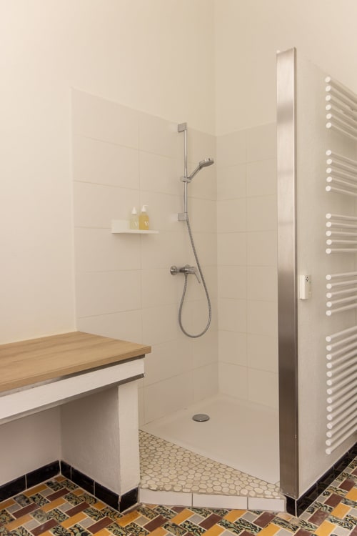 Modern bathroom with walk-in shower, heated towel rack, and wooden vanity at Le Prieuré Notre-Dame in Montfrin, France