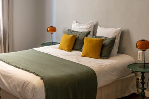 Chambre moderne au gîte Le Prieuré Notre-Dame à Montfrin avec lit blanc, oreillers jaunes et lampes ambrées