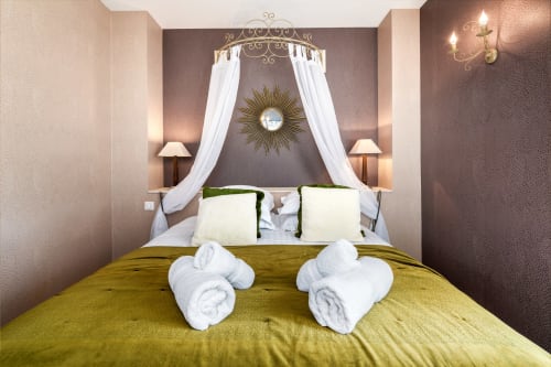 Luxe hemelbed met witte gordijnen en gouden zonnespiegels in de kamer Brume de Rêve, Domaine De Campagnac, Carsac-Aillac