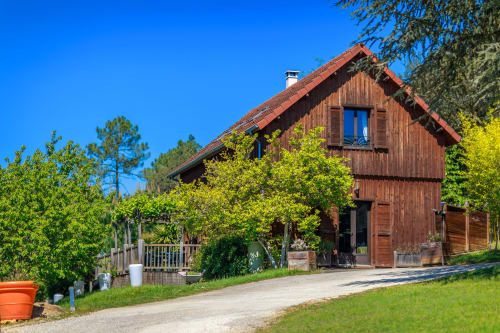 Rustieke houten cottage op Domaine De Campagnac in Carsac-Aillac met tuinuitzicht, terracotta dak en weelderig groen