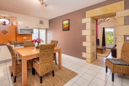 Eetkamer in Gîte la Bergerie van Domaine De Campagnac met houten tafel, rieten stoelen en mauveachtige accentmuren