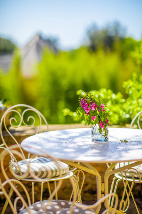 Buitenpatiötafel met roze bloemen bij gîte Domaine De Campagnac in Carsac-Aillac, omgeven door weelderige tuinen