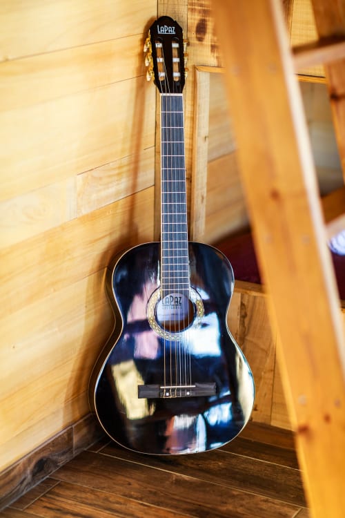 Zwarte klassieke gitaar tentoongesteld in een houten kamer in Domaine De Campagnac, een Frans bed & breakfast in Carsac-Aillac