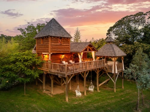 Tobago boomhuiskaamer bij Domaine De Campagnac met verlicht houten structuur en tuinzicht bij zonsondergang, Carsac-Aillac