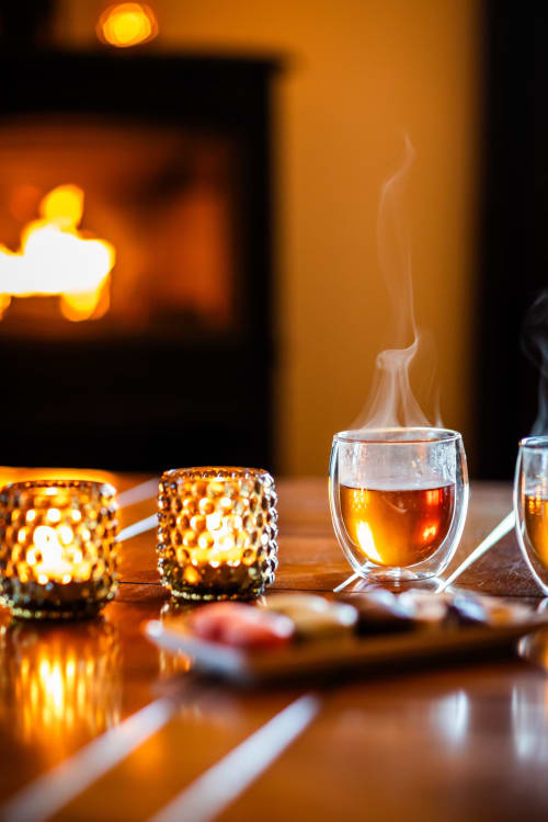 Warme amber cocktail met damp in glas naast gloeiende kaarsen in het luxe B&B Domaine De Campagnac in Carsac-Aillac