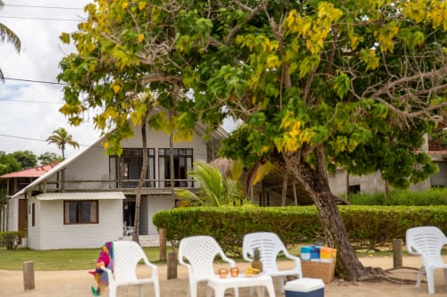 Villa frente al mar en Olamar Living con tumbonas blancas bajo árbol frondoso, playa arenosa en Coveñas, Colombia