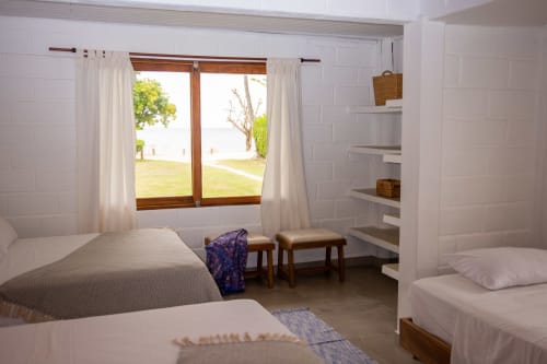 Luminoso dormitorio de villa en Olamar Living, Santiago de Tolú, con camas gemelas, vista al mar desde puertas dobles y zona de estar