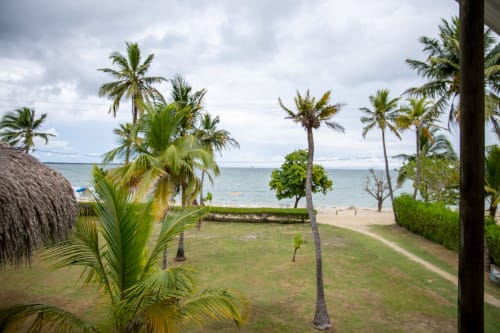Vista tropical frente al mar en villa Olamar Living, Santiago de Tolú, con palmeras, playa de arena y Caribe turquesa